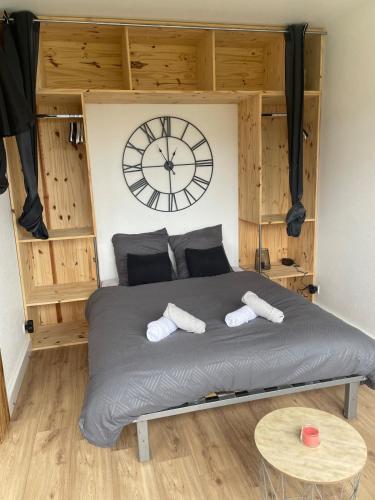 a bedroom with a large bed with a clock on the wall at Le Doubs Studio in Pontarlier