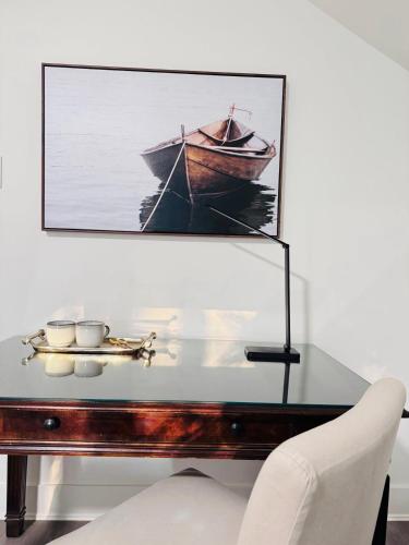 a painting of a boat on a table with a chair at Charming Queen Bedroom with Bathroom Vancouver West in Vancouver