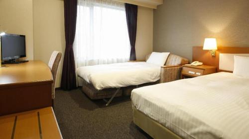a hotel room with two beds and a television at Ako Park Hotel in Ako