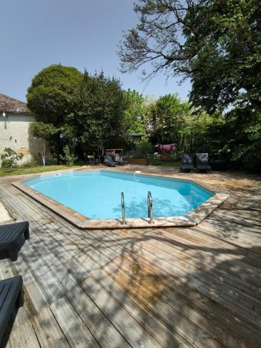 a swimming pool in a yard with a wooden deck at Gîte du château au pied de Cognac in Cherves-de-Cognac