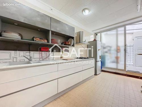 une cuisine avec des placards blancs et une grande fenêtre dans l'établissement chez l'habitant, à Lavelanet