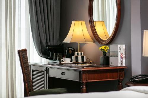 a bedroom with a desk with a lamp and a mirror at La Sinfonía Majesty Hotel and Spa in Hanoi