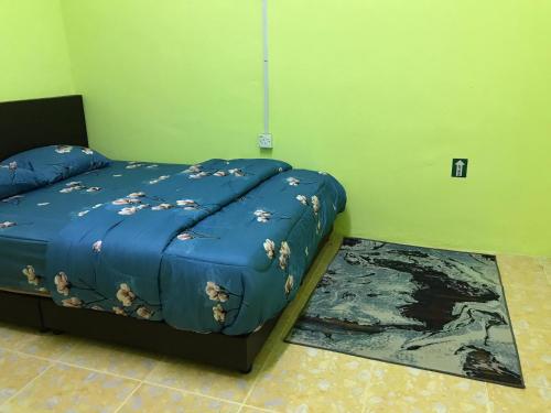 a bedroom with a bed with a blue comforter at Homestay D'Besut in Kampung Raja