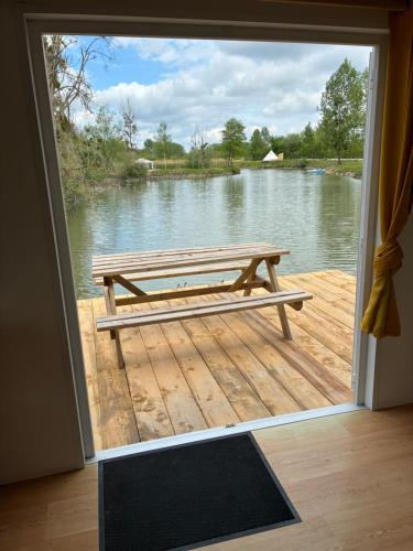une porte ouverte sur un patio avec un banc sur un quai dans l'établissement Mobile home du lac, à Clérey