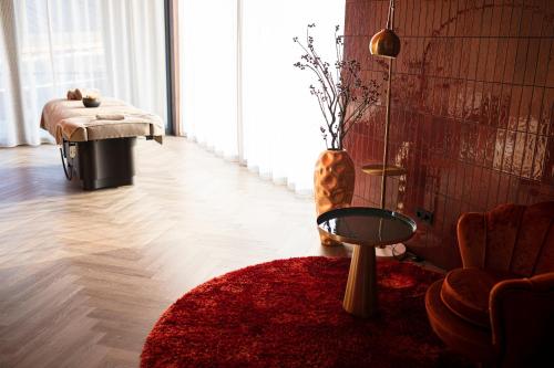 a living room with a red rug and a table at Das König Ludwig Inspiration SPA in Schwangau