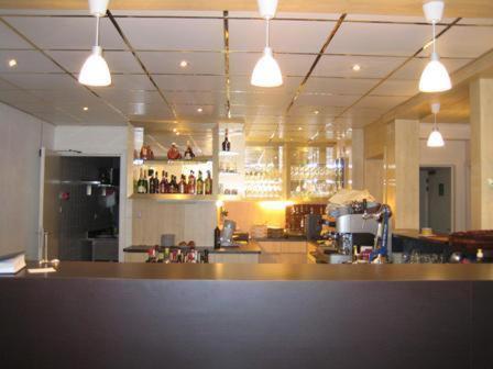 a bar in a restaurant with a counter and lights at Hotel Asian Empire in Kuurne