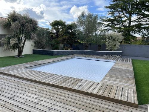 une piscine dans un jardin avec une terrasse en bois dans l'établissement Magnifique villa, piscine, 4 chb, sans vis à vis, Marais Poitevin, à Magné