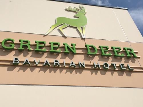 una señal de ciervo verde en el lateral de un edificio en Green Deer Bavarian Hotel en Langenbruck