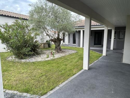 une maison avec un arbre dans la cour avant dans l'établissement Magnifique villa, piscine, 4 chb, sans vis à vis, Marais Poitevin, à Magné