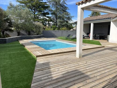 une arrière-cour avec une terrasse en bois et une piscine dans l'établissement Magnifique villa, piscine, 4 chb, sans vis à vis, Marais Poitevin, à Magné