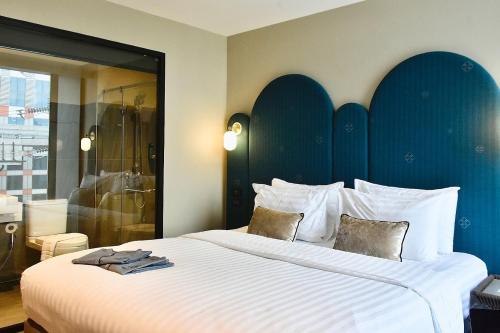 a bedroom with a large bed with a blue headboard at Benjarong Hotel Bangkok in Ban Zong Katiam