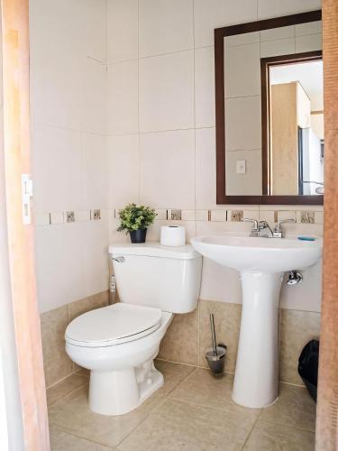 a white bathroom with a toilet and a sink at Aruba , Eagle Beach Townhouse in Palm-Eagle Beach