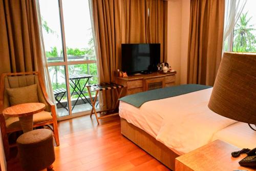 a hotel room with a bed and a television and a balcony at Seasalter Maldives in Hulhumale