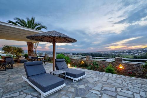 a patio with two chairs and an umbrella at Pyrgaki Hotel in Parikia