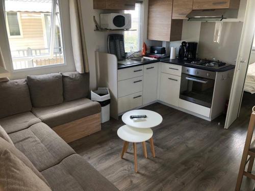 un salon avec un canapé et une table et une cuisine dans l'établissement MOBIL HOME l'EDEN, à Sérignan