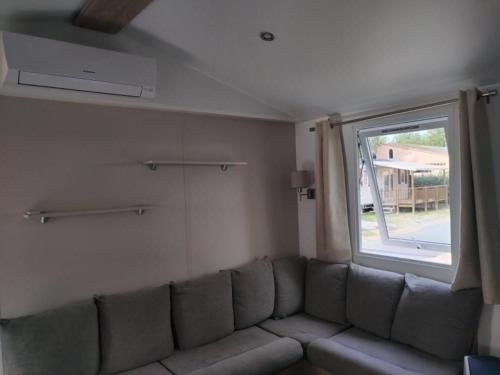 un canapé dans un salon avec une fenêtre dans l'établissement MOBIL HOME l'EDEN, à Sérignan