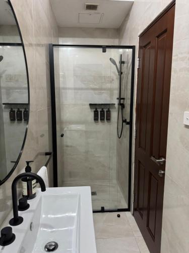 a bathroom with a shower with a sink and a mirror at Chez Mimi, Elegant City Escape in Sydney
