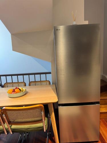 a stainless steel refrigerator next to a table with a bowl of fruit at Chez Mimi, Elegant City Escape in Sydney