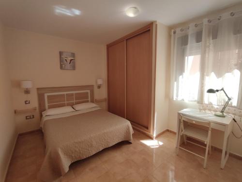 Un dormitorio con una cama y una mesa y una ventana. en Apartamento fuerte, en Puerto del Rosario