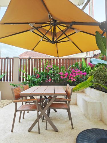 a picnic table and two chairs under a yellow umbrella at The Palm House in Dauis