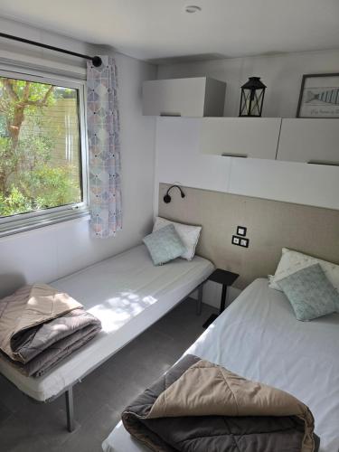 une chambre avec deux lits et une fenêtre dans l'établissement Mobil home 3 ch 6 pers Camping Mayotte, à Biscarrosse