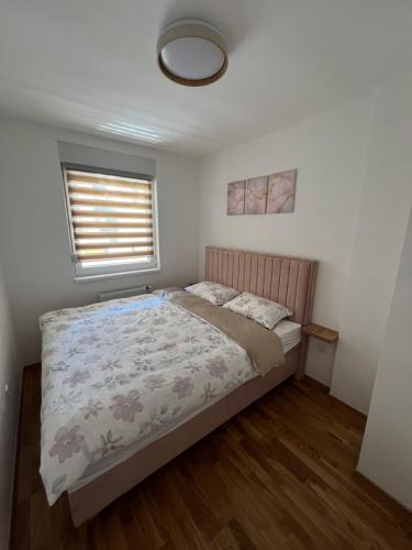 a bedroom with a bed and a window at Elita Apartmani in Ivišovo Greblje