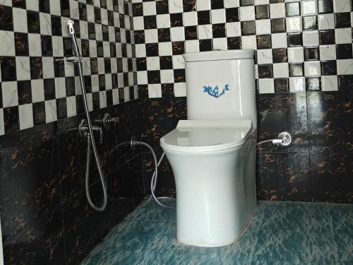 a white toilet in a bathroom with a checkered wall at CSR Palace Langasu By StayApart in Karnaprayāg