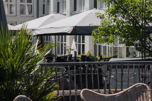a table and chairs with umbrellas on a balcony at Hotel Raphael im Allgäu in Kempten