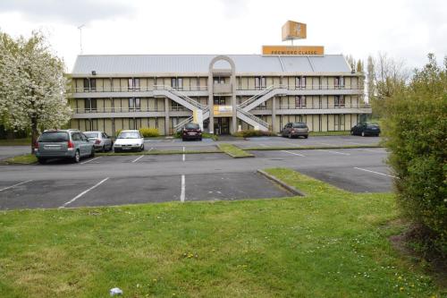 a large building with cars parked in a parking lot at Premiere Classe Lille Sud - Douai Cuincy in Cuincy