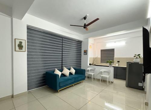Una sala de estar con un sofá azul y una cocina. en Lakshmi Home, en Trichūr