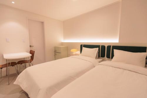 two beds in a room with a desk and a table at Wecostay Cheongnyangni in Seoul