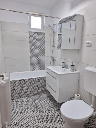 a white bathroom with a toilet and a sink at Panoramic Apartment in Gherla
