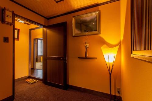 a hallway with a floor lamp and a door at Ryokan Asunaro in Takayama