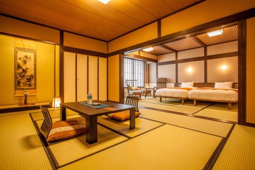 a bedroom with two beds and a table and chairs at Ryokan Asunaro in Takayama