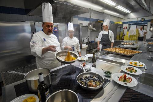 a group of chefs in a kitchen preparing food at Ecoresort Le Sirene - Caroli Hotels in Gallipoli