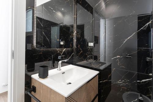 a bathroom with a white sink and black marble walls at ApartHotel Angelo - Salento Reservation in Racale