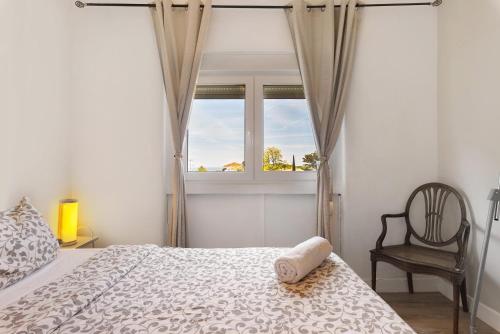 a bedroom with a bed and a chair and a window at Bisa's house in Estoril