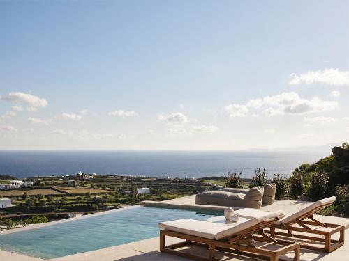 a view of a pool with a lounge chair and the ocean at Stamna Sifnos a member of Design Hotels in Sifnos