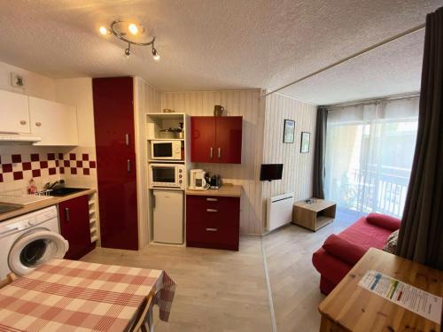 une petite cuisine avec des placards rouges et un salon dans l'établissement Résidence Oncet - Appartement 5 couchages dans le centre de Barèges MAE-0883, à Barèges