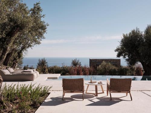 a patio with two chairs and a table and a couch at Stamna Sifnos a member of Design Hotels in Sifnos