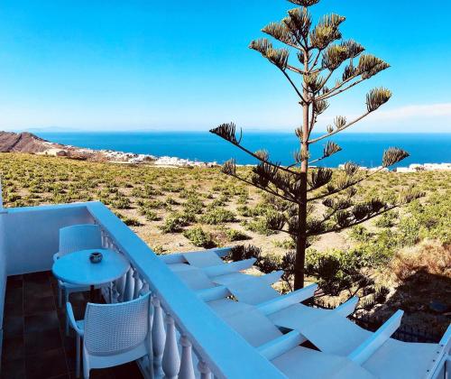 a balcony with a tree and a table and chairs at Villa Happening in Imerovigli