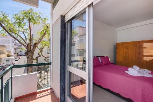 a bedroom with a pink bed and a balcony at Apartamento Gaspar in Vila Real de Santo António