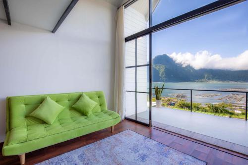 a living room with a green couch and a large window at Faro Cabin Kintamani in Kintamani
