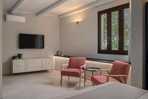 a bedroom with two chairs and a tv on the wall at Villa Felicia in Noto