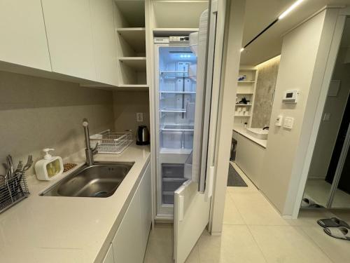 a kitchen with a sink and an empty refrigerator at Lotte Tower view terrace house in Seoul