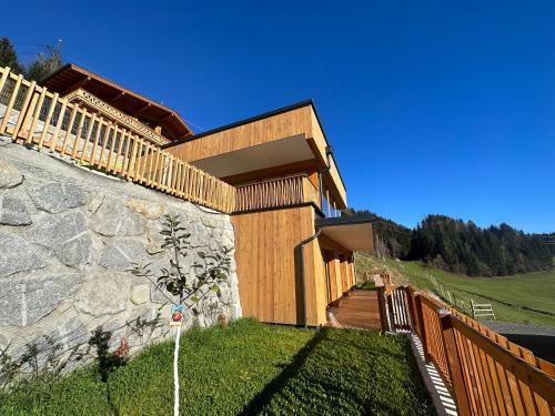a house with a wooden fence and a stone wall at Exklusives Chalet-Haus mit Gletscherblick in Neukirchen am Großvenediger