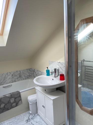 a bathroom with a sink and a bath tub at The Coach House in Wareham