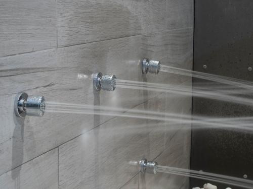 a shower with two shower heads and a glass wall at Albergue Spa Cruceiro de Pedrouzo in O Pedrouzo