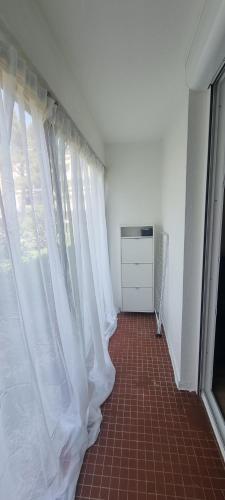 un couloir avec des rideaux blancs et un sol en carrelage rouge dans l'établissement Appartement, à Aix-en-Provence