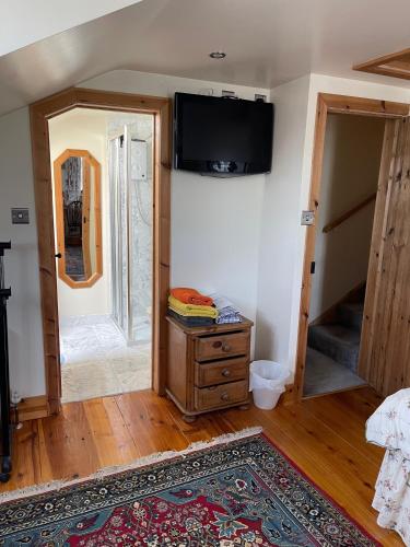a room with a tv on the wall and a dresser at The Coach House in Wareham